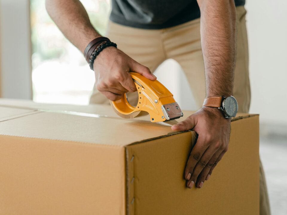 a man taping a cardboard box with tape