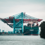 very big metal cranes and steel ships in the docks