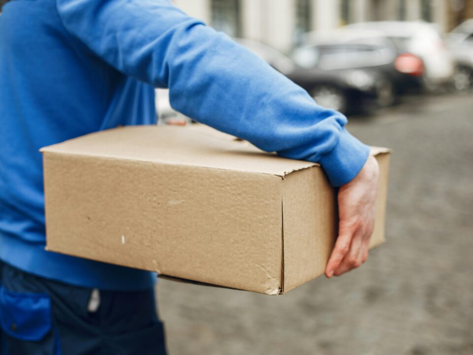 The courier walks down the street, holding the package.