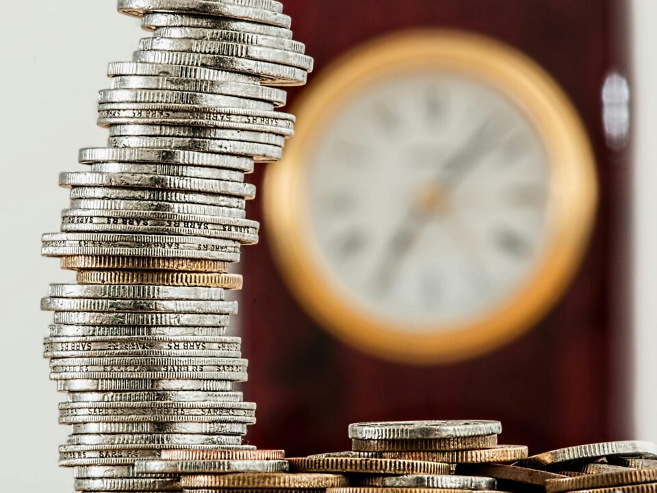 A pile of coins, with a blurred clock in the background
